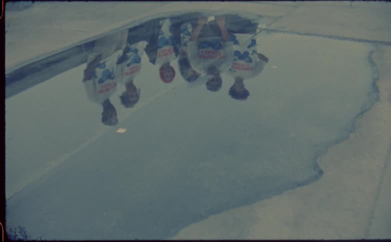 Reflection of a group of friends on a small pool of water on the roof of a building