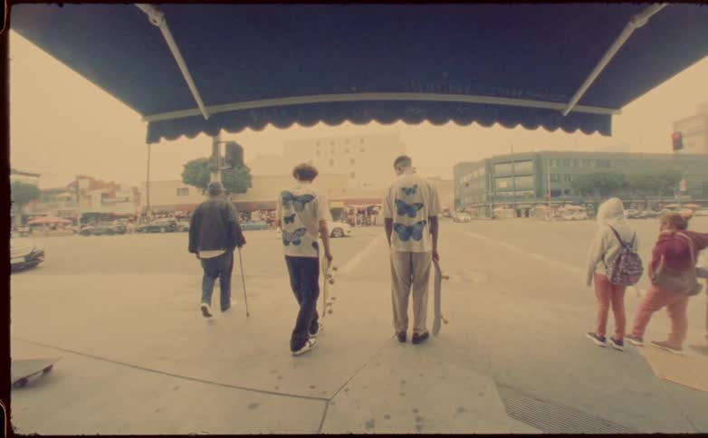 Two young men standing on the entrance of a building looking at the street with skateboards on their hands