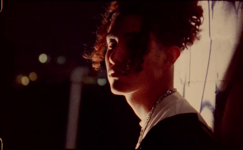 A man is modeling for the camera outdoors at night