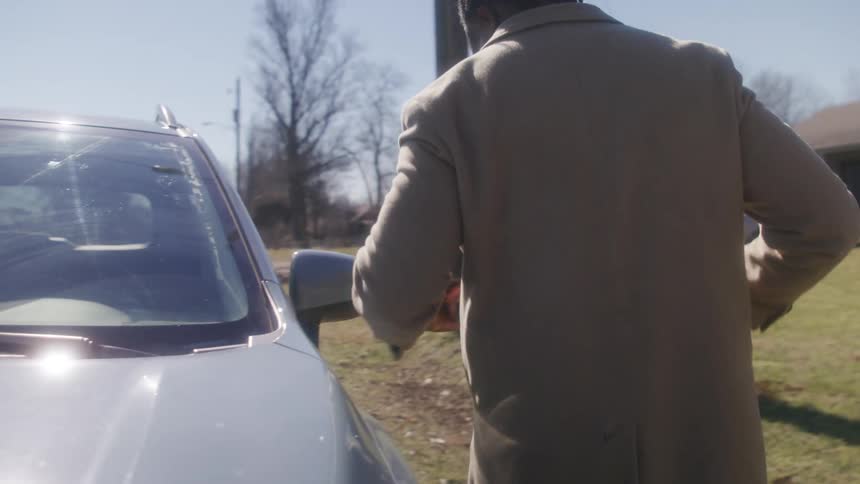 A man walks and gets into his car