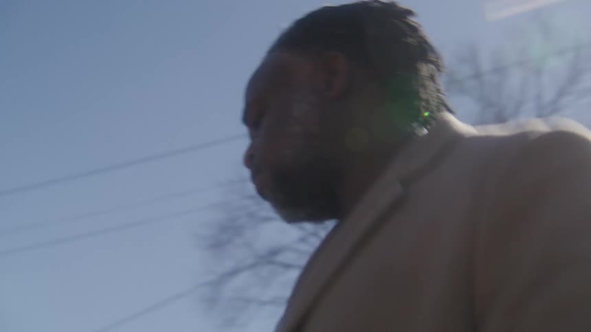 Man exits a car parked on the curb of a road to open the hood