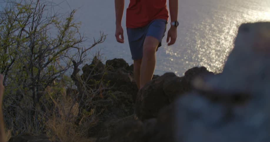 A man walks up a hill on the shore