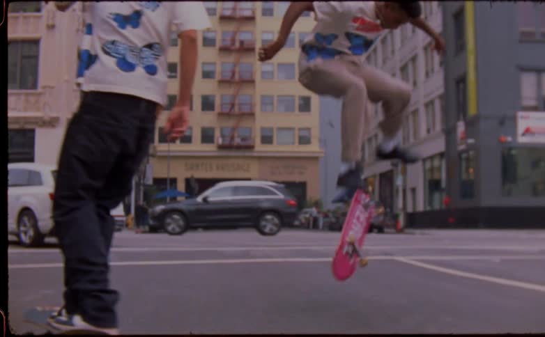Two people are skateboarding down the busy street