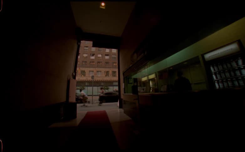 Interior view from a narrow lobby of two people skateboarding by
