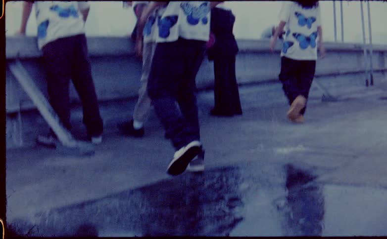 Group of friends walk over a puddle on the roof of a building to look at the city