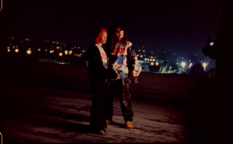 Two young girls modeling for the camera on a photo shoot on the roof of a building at night