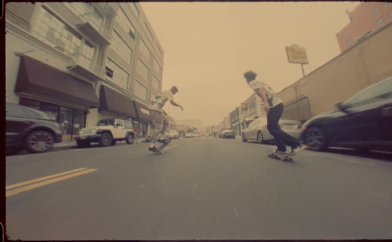 Two young men riding skateboards on the city street at daytime