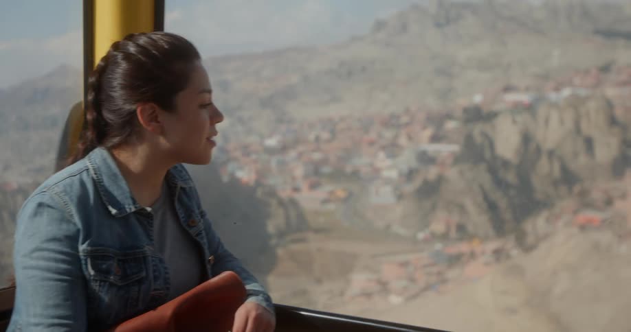 Young woman looking at a small mountain town from a moving cable car