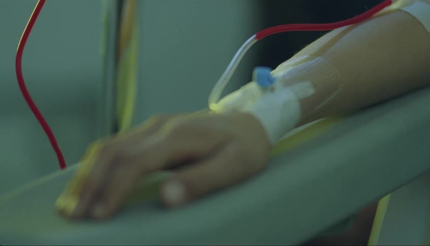 Blood flows along iv line during transfusion into person sitting with arm propped on surface