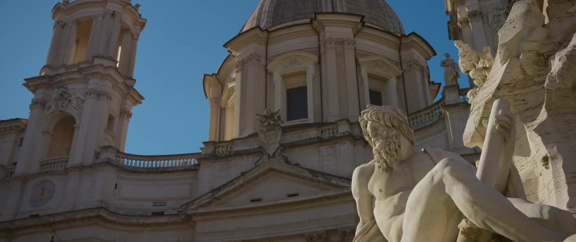 Sculptures of bearded men sit in front of a domed building
