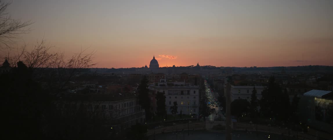 Aerial view of city skyline with domes and vehicles driving on highway and buildings at sunset
