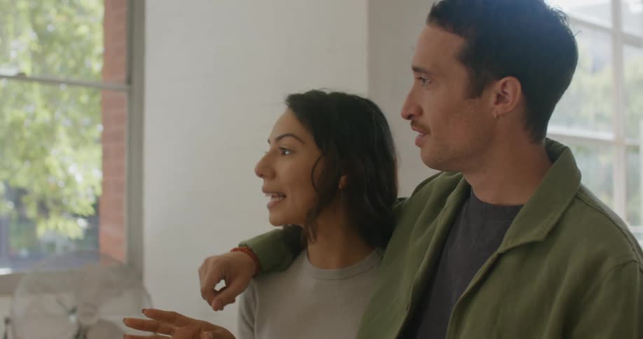 A man and woman look out the window together
