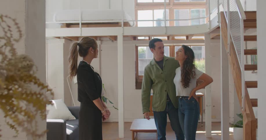 A man and woman stand and admire the interior of a residence that they are touring with a realtor