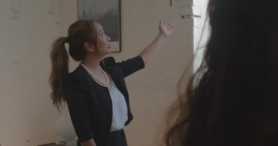 A woman points at a window as she shows a property to clients
