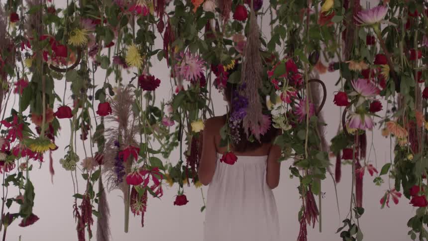 White-gowned woman standing amongst hanging flowers