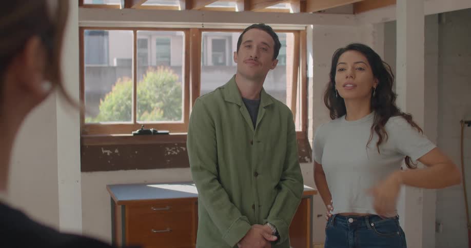 A man and woman look around the interior of a residence as their realtor stands nearby