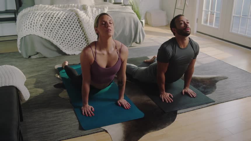 Two people perform yoga in the bedroom