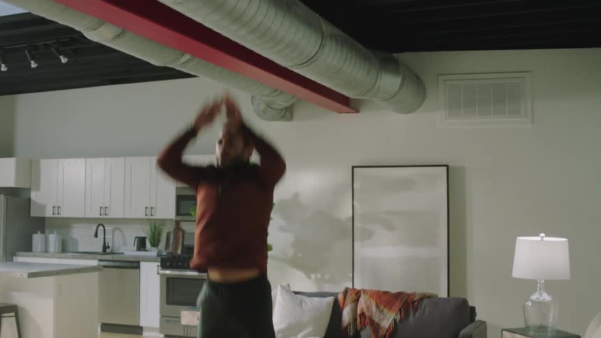 A man works out in his living room performing push up squat jumps