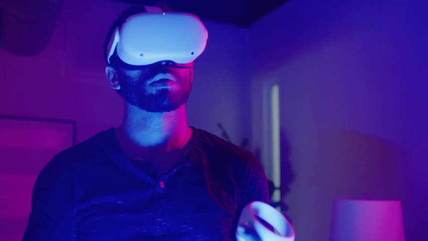 A man is wearing a virtual reality headset and using controllers in a room
