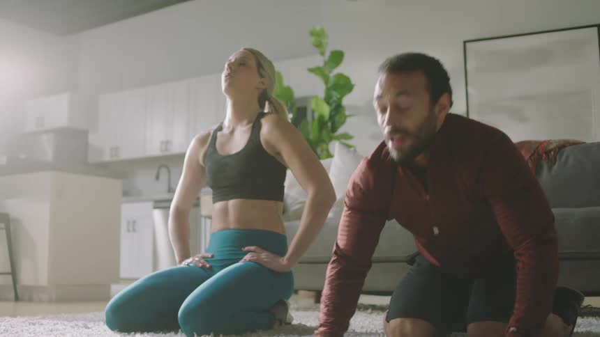 Man and woman are exercising together in a living room