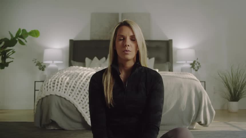 Woman sits on floor in bedroom meditating and deep breathing