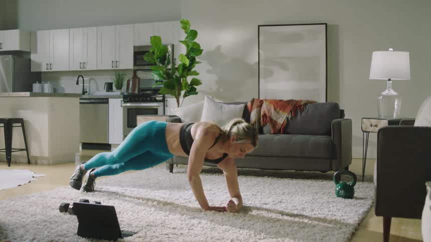 A woman lifts weights and does yoga at home