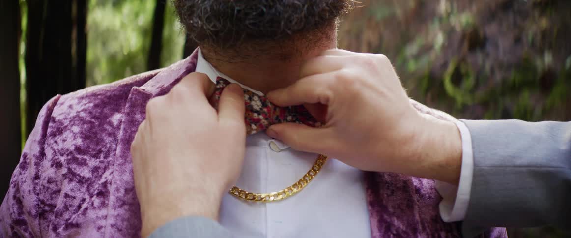 A man is having his bow tie adjusted