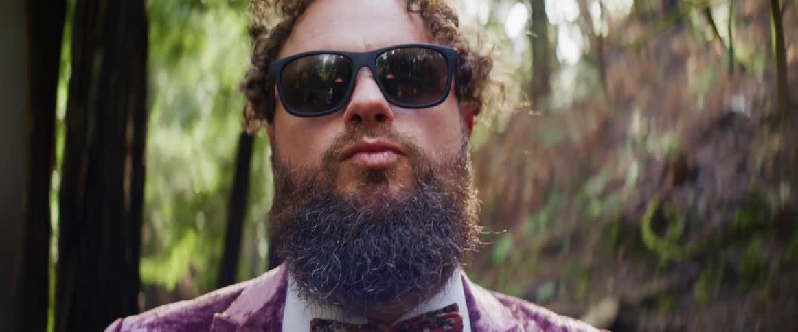 A man dressed in a purple suit making a kissy face
