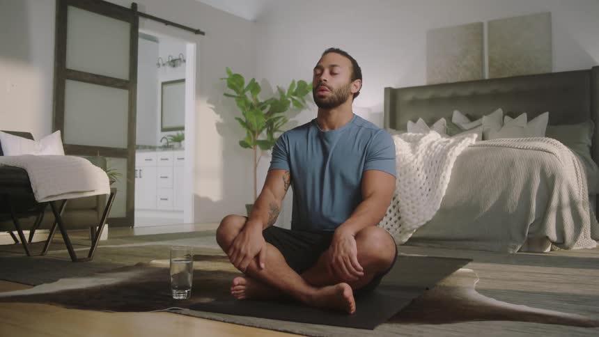 A man is doing yoga in his bedroom during the daytime