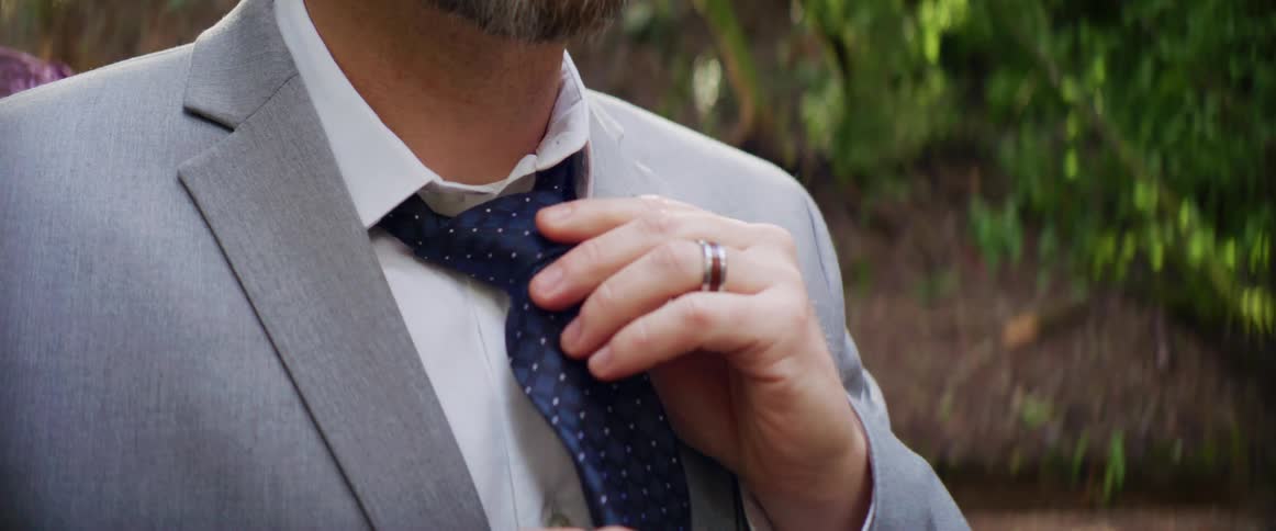 A man putting on a tie outdoors