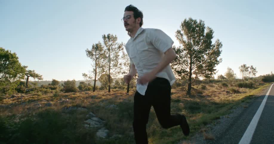 A man runs along the side of a road through a rocky field on a clear day