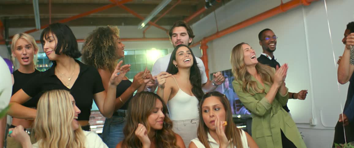Group of friends sitting and standing around a table in a party dancing together in a choreography