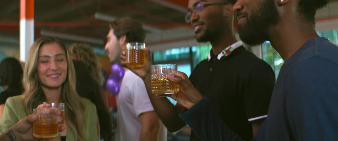 A group of people talking and laughing while holding drinks at a gathering
