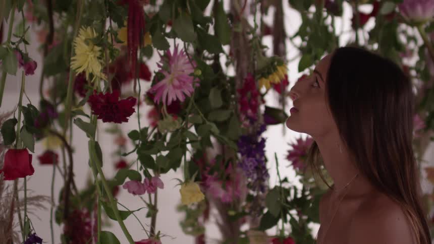 A woman looks up at vines with flowers