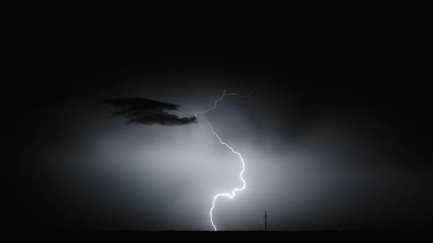 Lightning strikes in rapid succession over a field and lights up the night sky