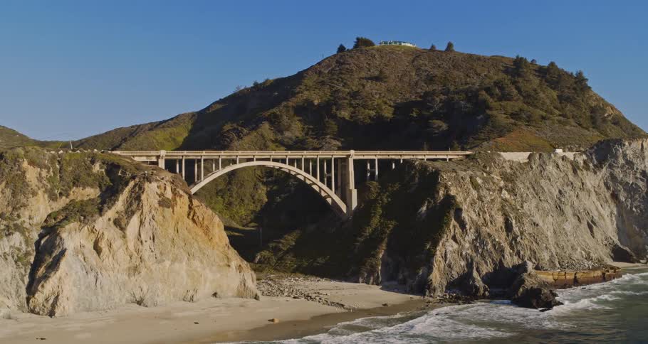 A vehicle driving over a coastal bridge in the daytime