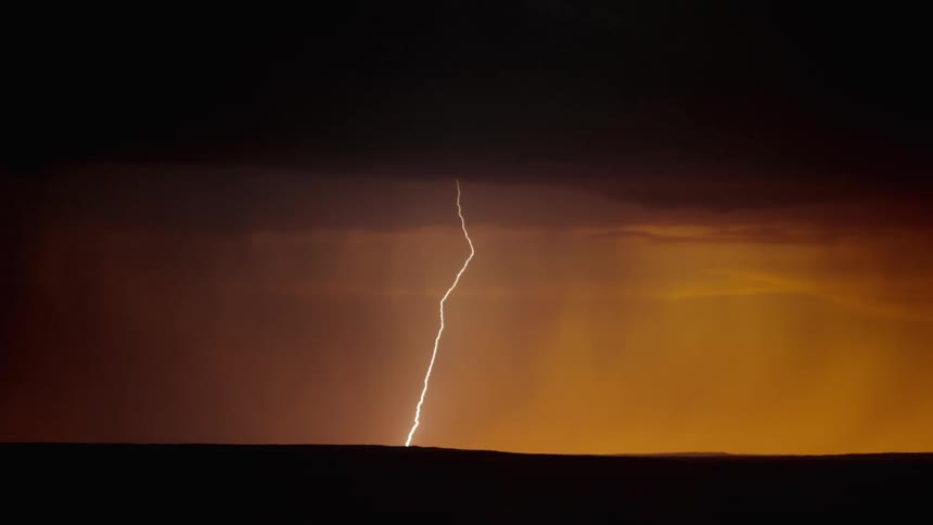 The night sky glows orange during a thunderstorm