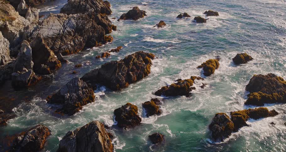 Aerial view of ocean waves moving towards the coast is displayed
