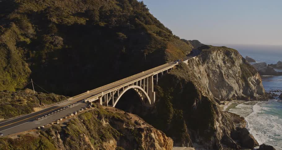 Cars are driving on a bridge near the coast of an ocean