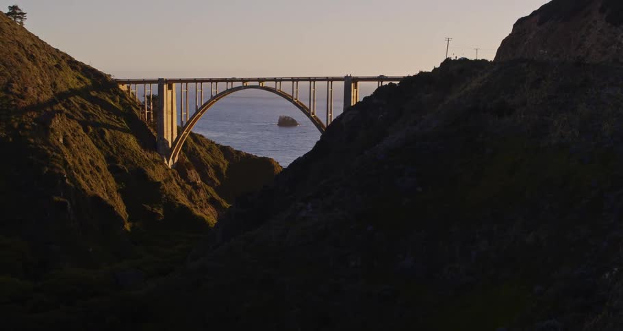 A vehicle drives over a bridge connection two sections of a promontory along the coast