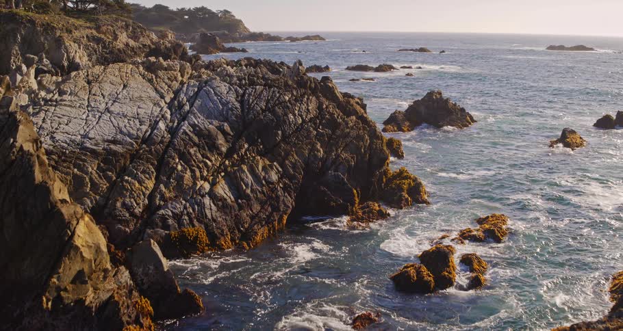 An aerial view of waves rolling in to a cliff on the shore