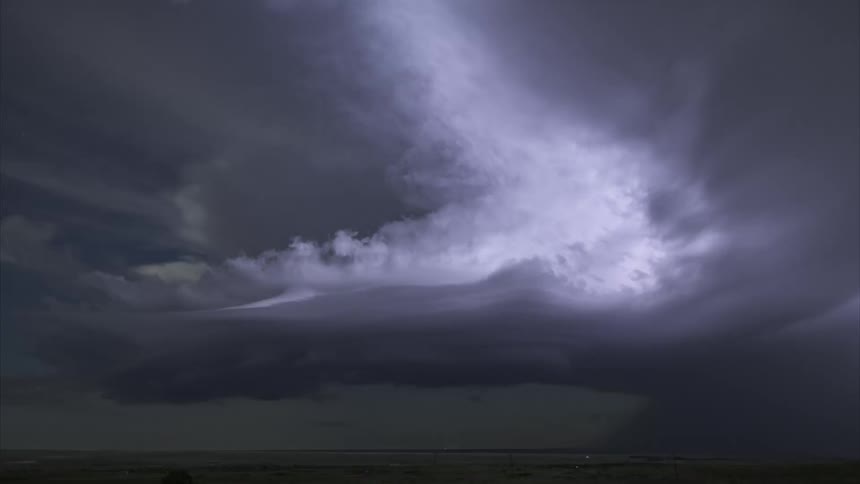Dark clouds and flashes of lightning over a field at night
