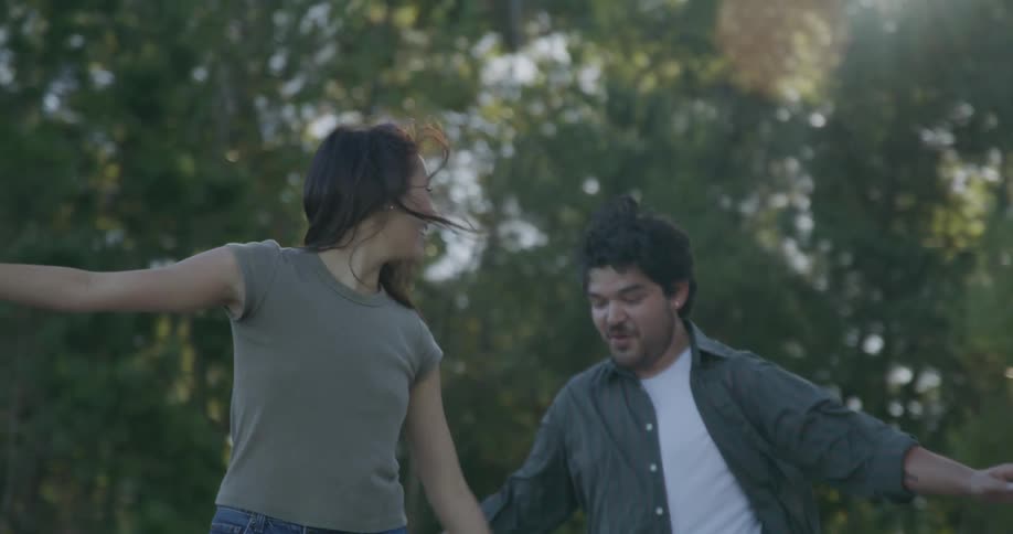 A couple pretend that theyre walking on a balance beam in the forest
