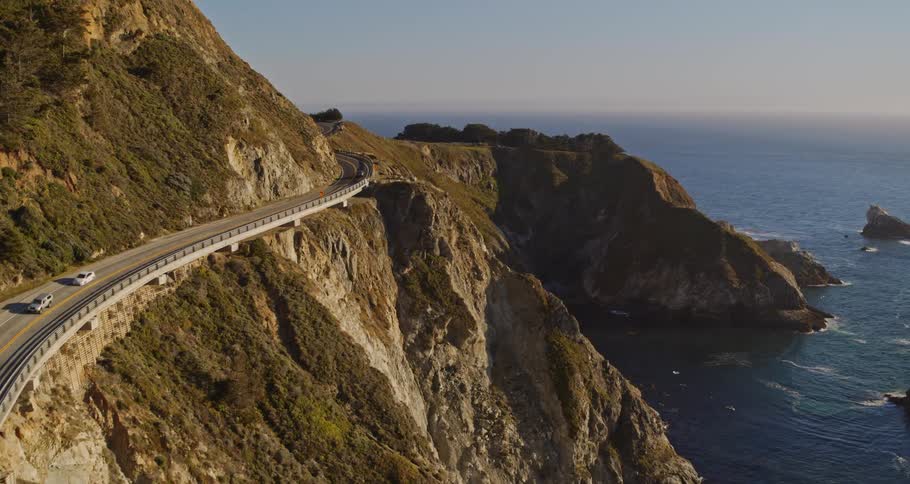 Aerial view of cars driving on bridge along the mountains