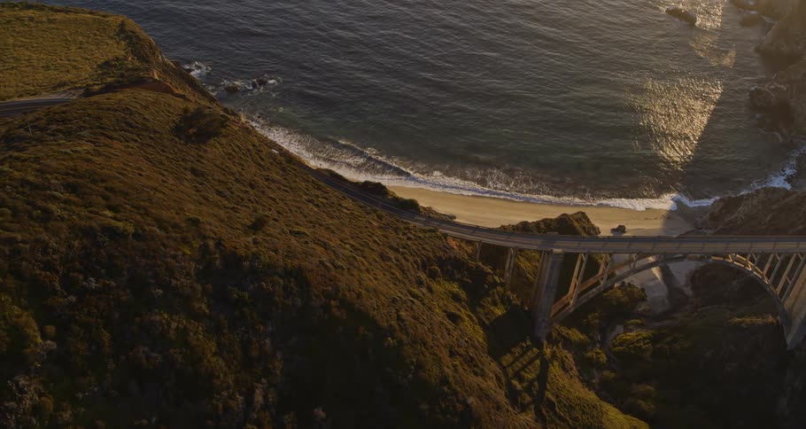 Vehicle travels over a bridge on a highway next to the beach and the ocean