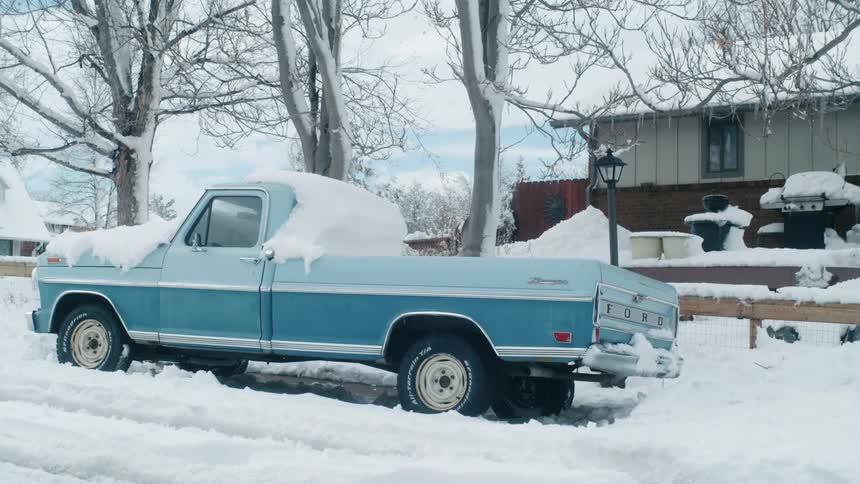 A truck is parked by a house in winter