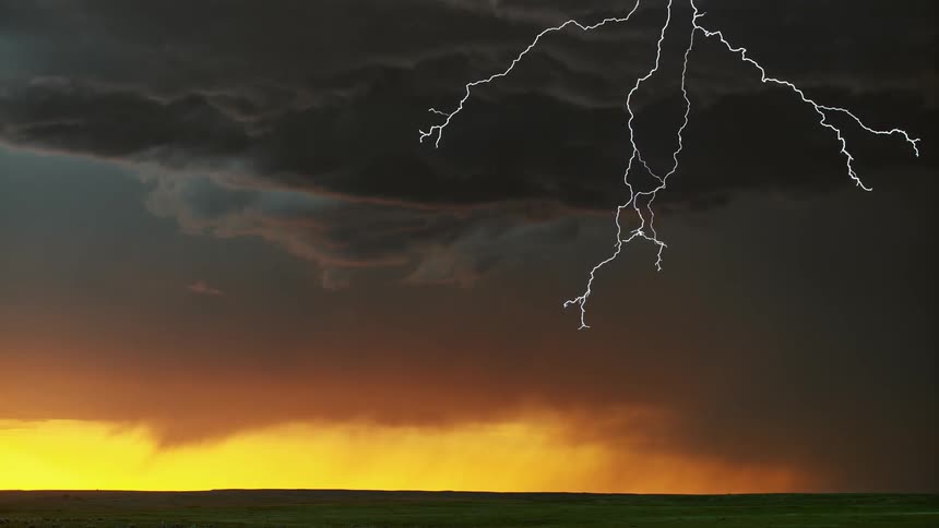 Lightning flashing in a cloudy sky during a thunderstorm at sunset