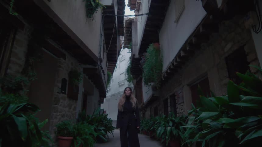 A woman walks down a pathway lined with plants at an apartment building