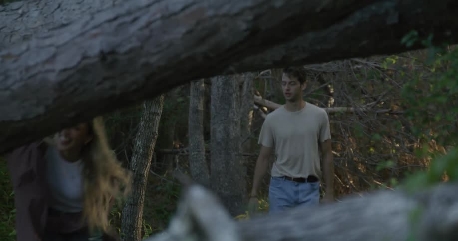 Woman with jacket white top and jeans and man wearing white shirt and jeans walk in the forest