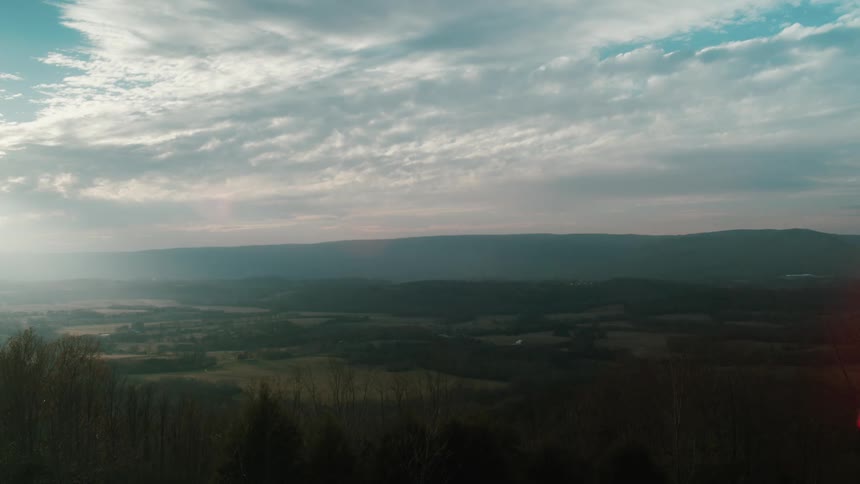 Aerial view of plains and distant mountain and shining sun